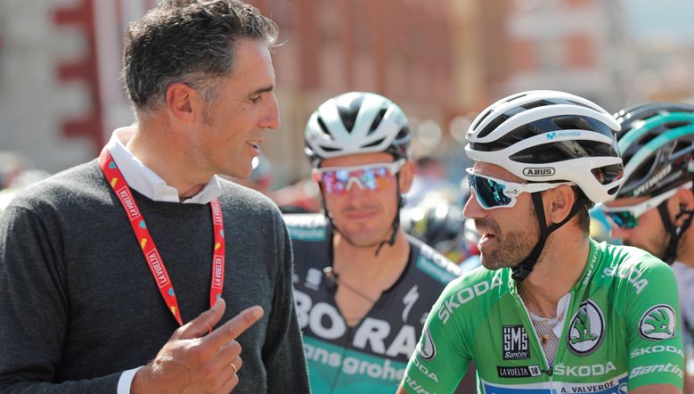 Miguel Indurain conversa con Alejandro Valverde en la salida de la decimocuarta etapa de la Vuelta 2018, en Cistierna. 