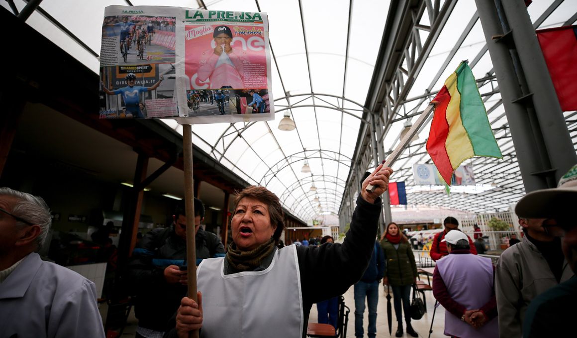 Una mujer sostiene una pancarta y una bandera para apoyar al ciclista ecuatoriano, ayer miércoles en la ciudad de Tulcán (Ecuador), durante su participación en el Giro de Italia. Foto: EFE