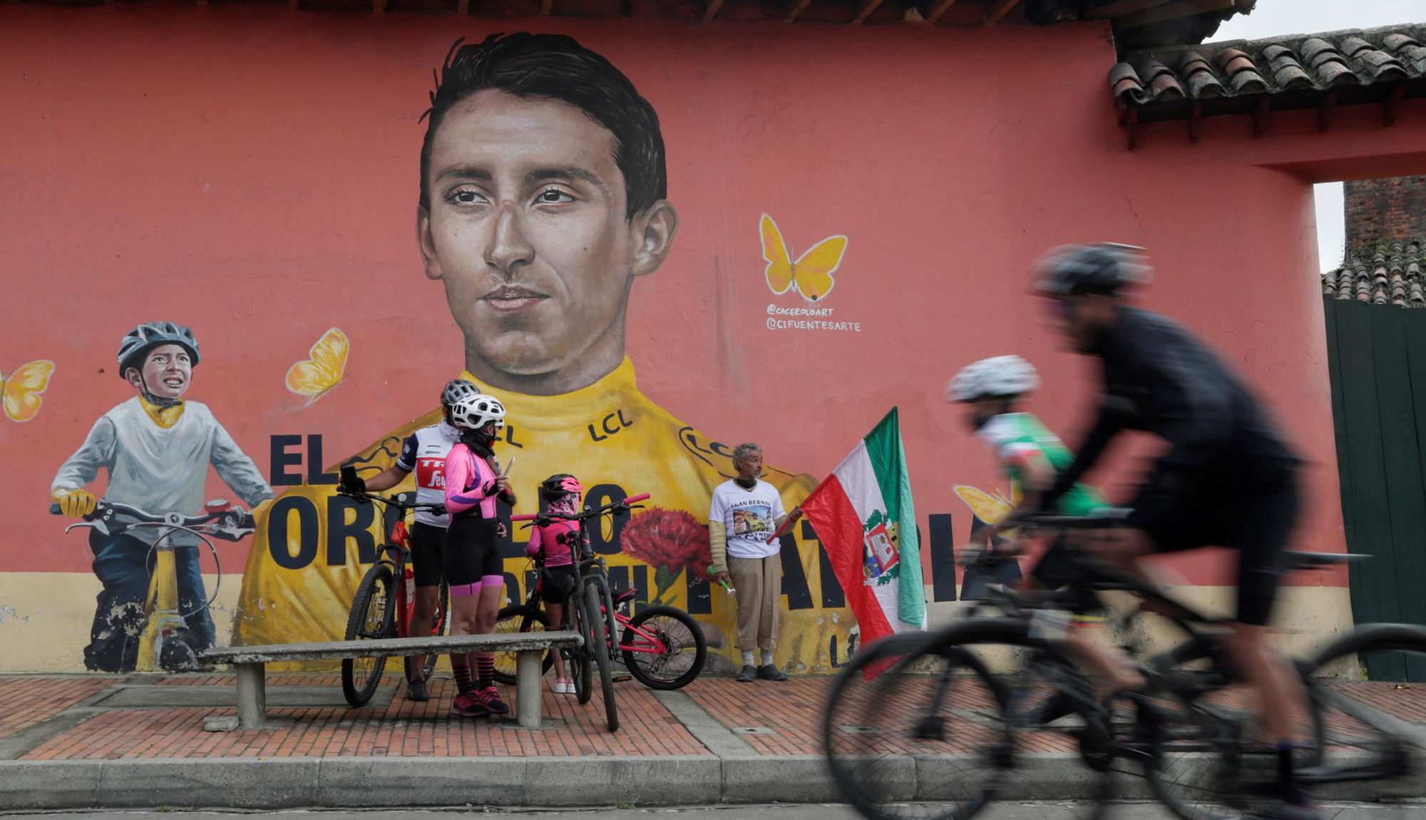 Ciclistas pasan frente a un mural con la imagen de Egan Bernal en Zipaquirá,