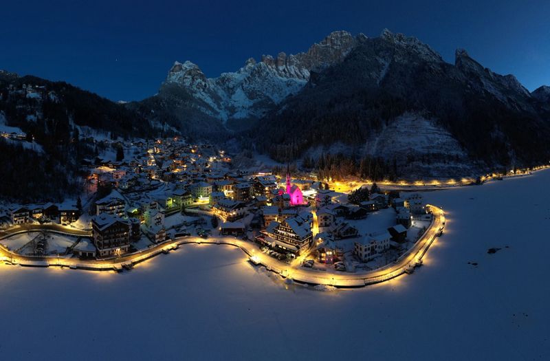 Una vista panorámica de Alleghe, donde la iglesia de San Biagio estaba iluminada de rosa. La etapa 19 terminará en Piani di Pezzè Una vista panorámica de Alleghe, donde la iglesia de San Biagio estaba iluminada de rosa. La etapa 19 terminará en Piani di Pezzè